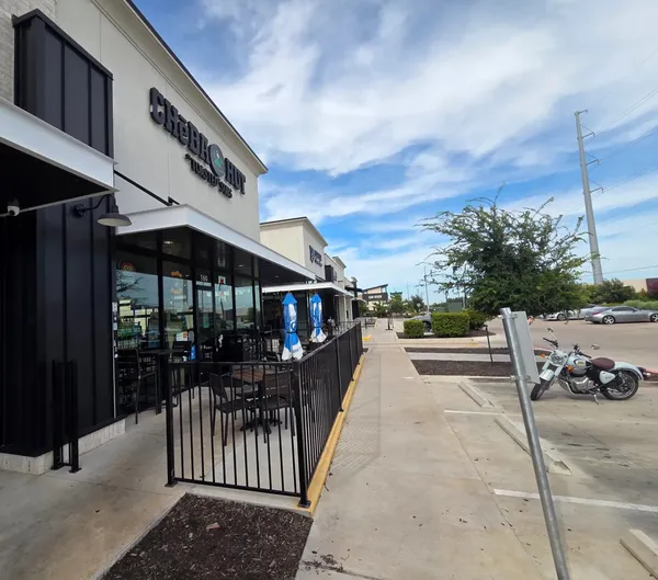 The Cheba Hut storefront, patio tables out front, Leander strip mall